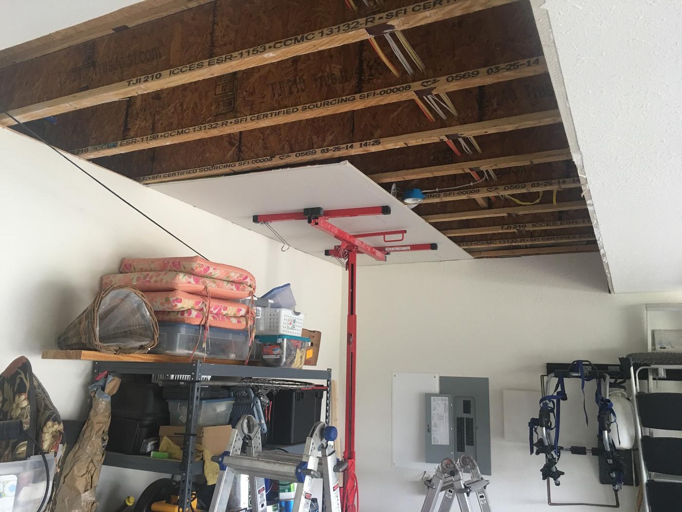 A garage ceiling going up, sheet by sheet, on a panel lift.