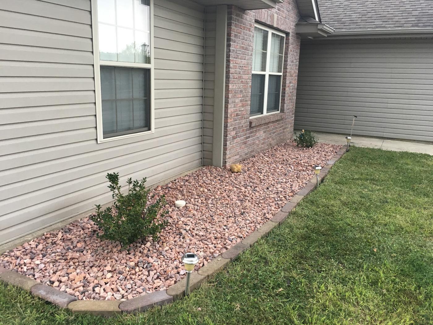 A bed run along the side of a house in pink-toned rock, edged with curved pavers.