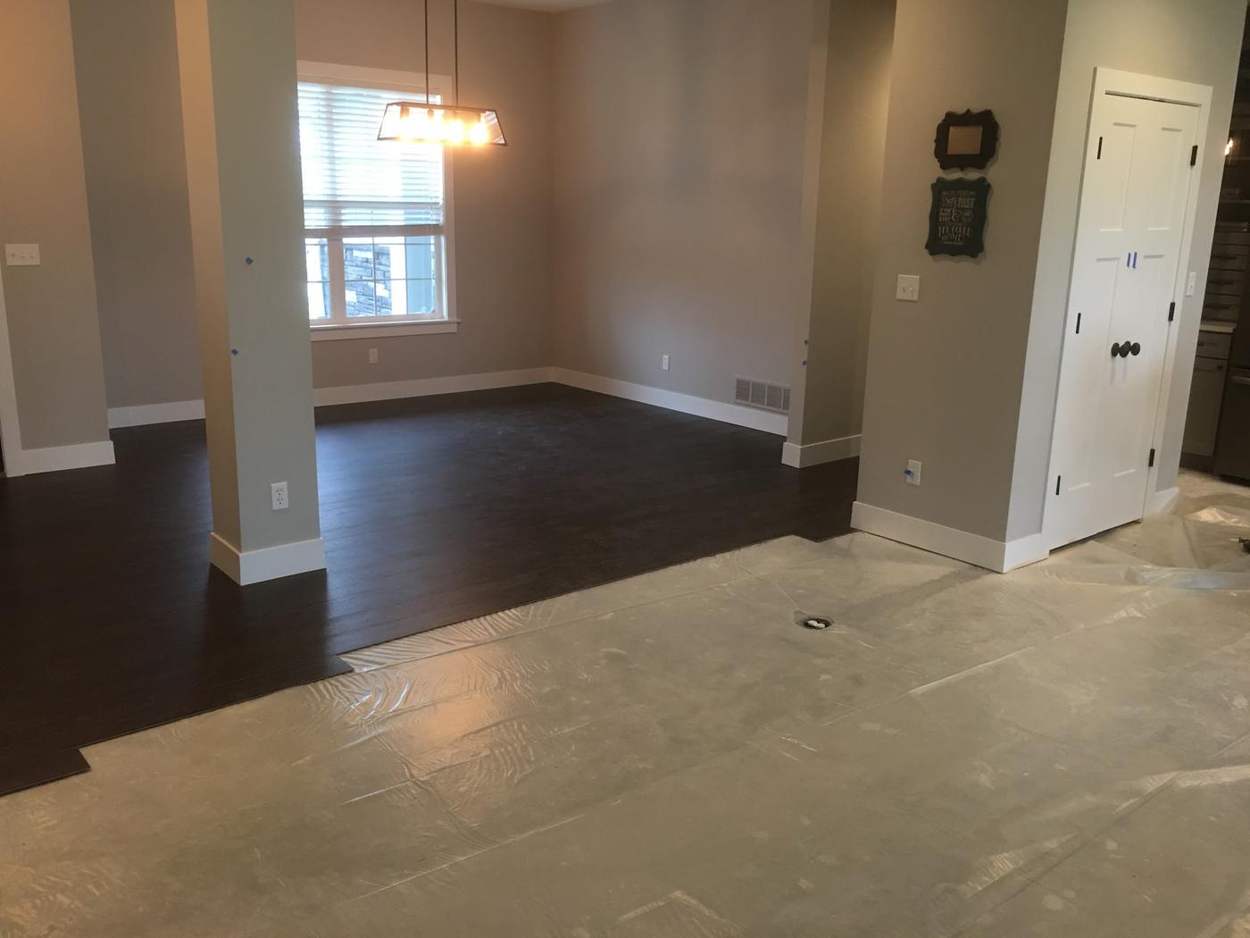 Dark plank flooring laid through a room, with the next room sheeted off to protect it.